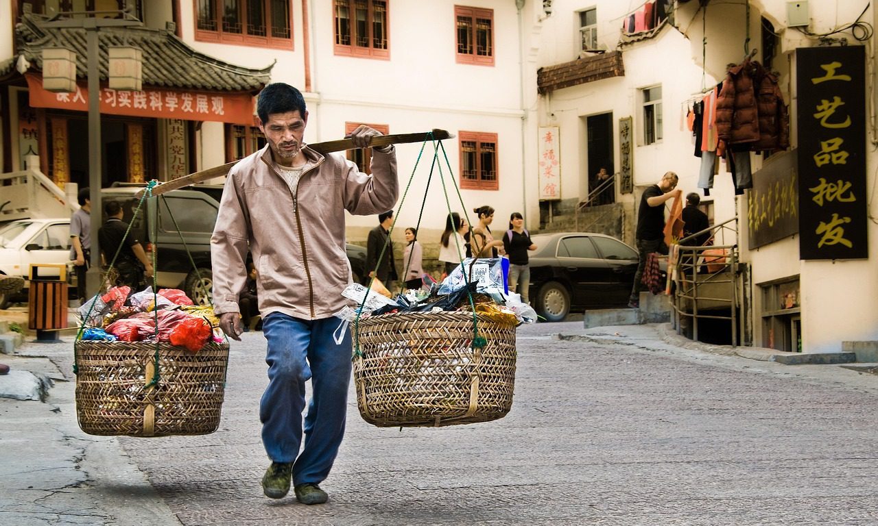 Czas pracy w Chinach: Chińczyk fizycznie pracujący idzie ulicą.