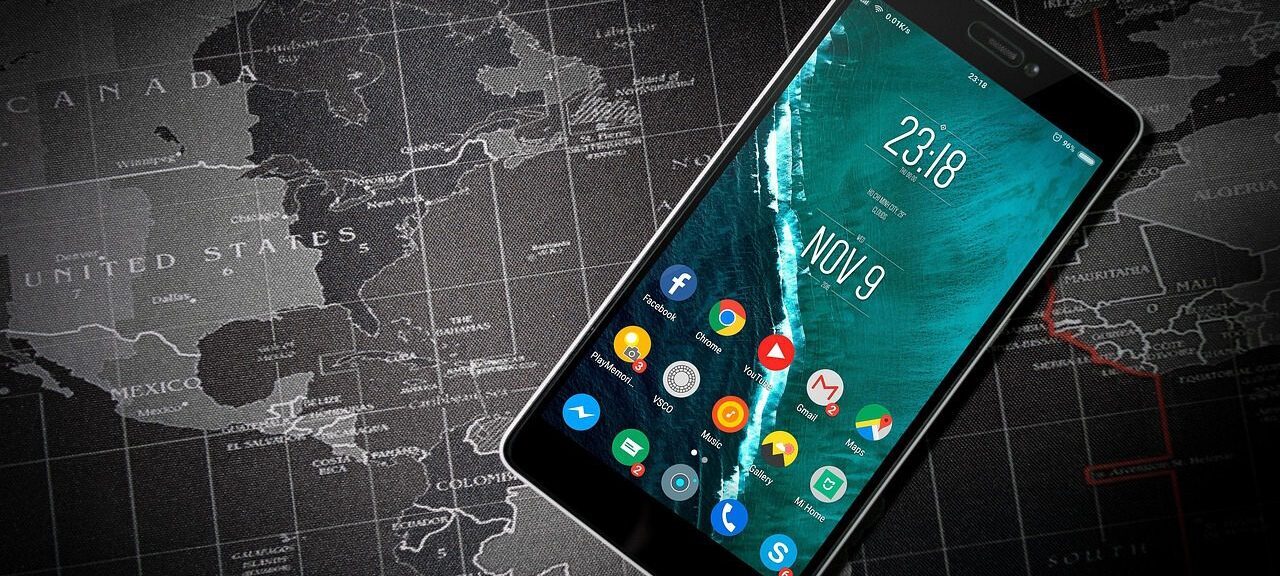 Telefon z aplikacjami położony na mapie świata