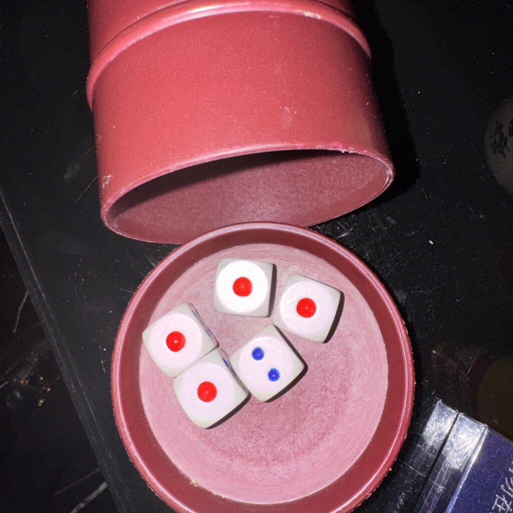 Kości w kubeczku: dwójka i cztery jedynki